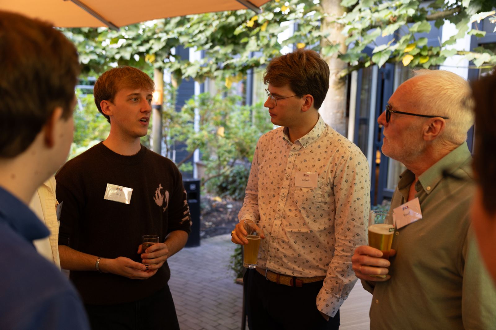 Drie mannen met naamkaartjes in gesprek tijdens de borrel