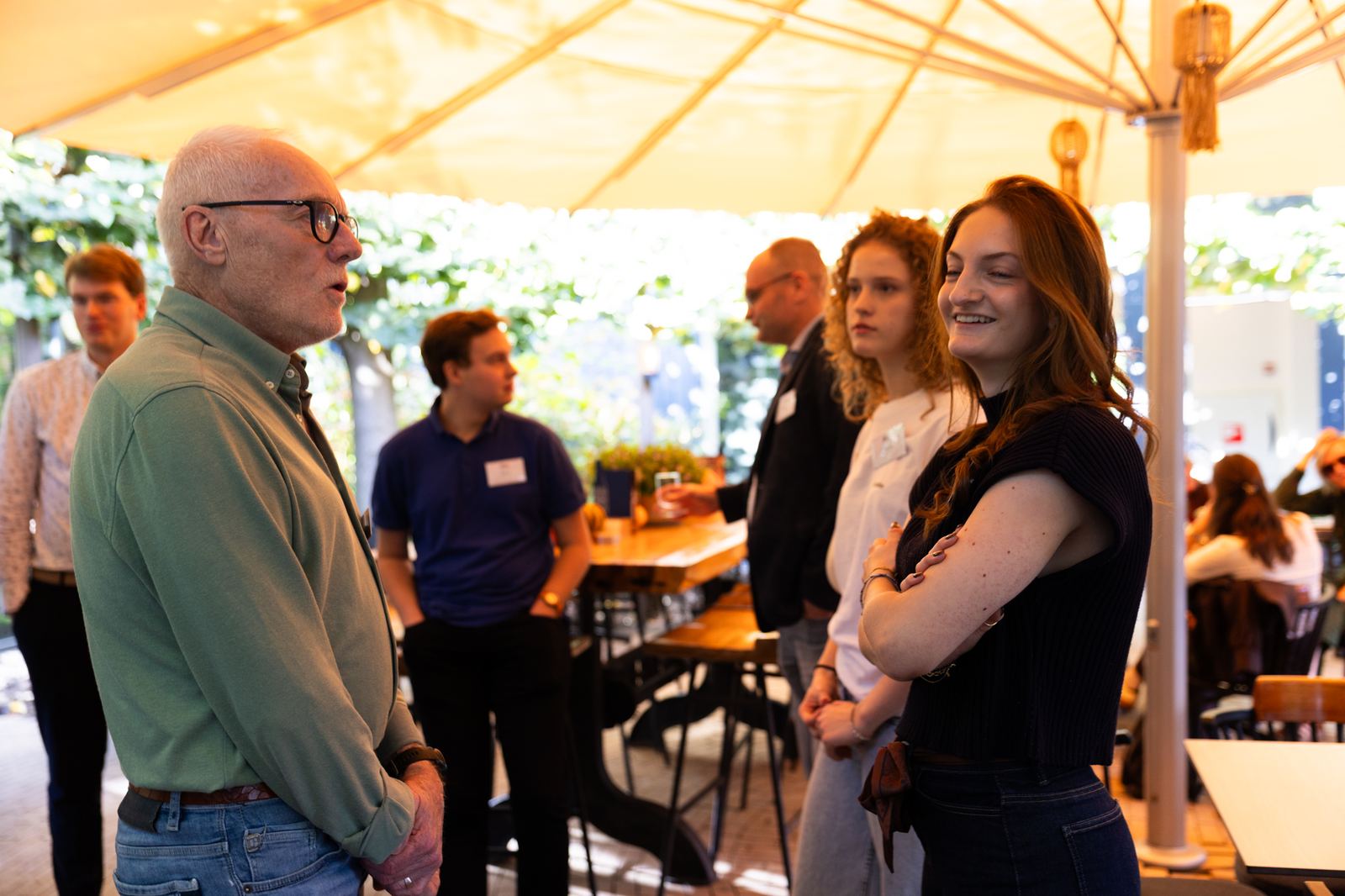 Deelnemers en Rotarians in gesprek onder een luifel